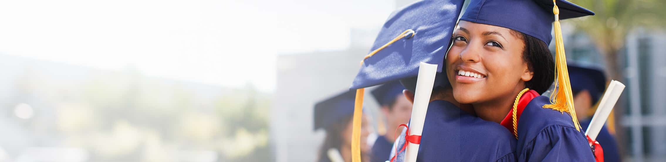 mother hugging daughter in graduation gown and cap