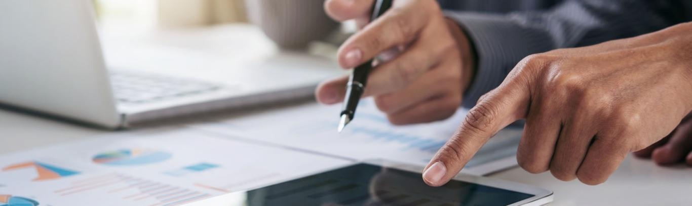 view of hands writing in notebooks and pointing to key statistics