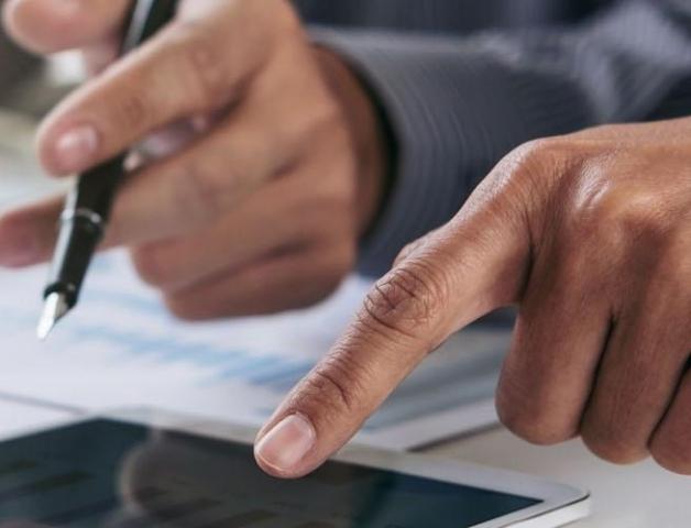 Hands holding a pen and using a tablet