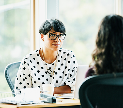 Woman behind desk talking with another woman