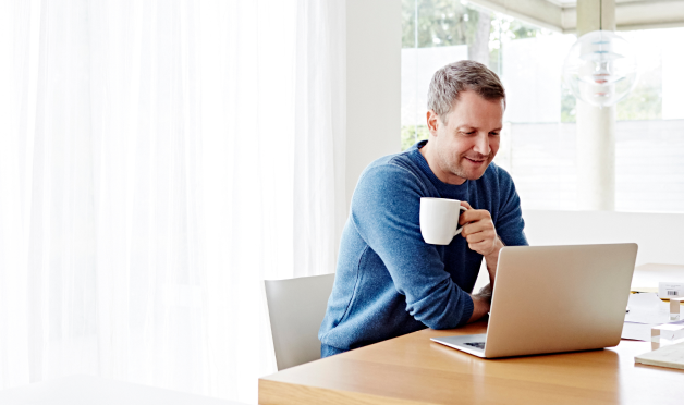 Man using a laptop holding a cup of coffee