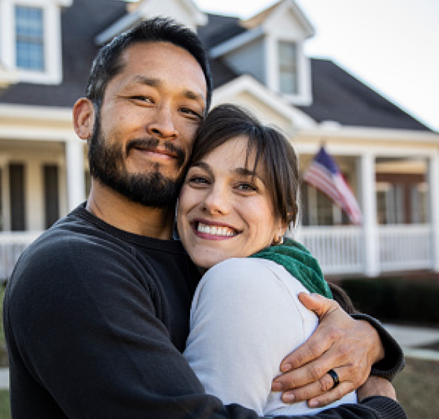 Couple hugging in front of their home