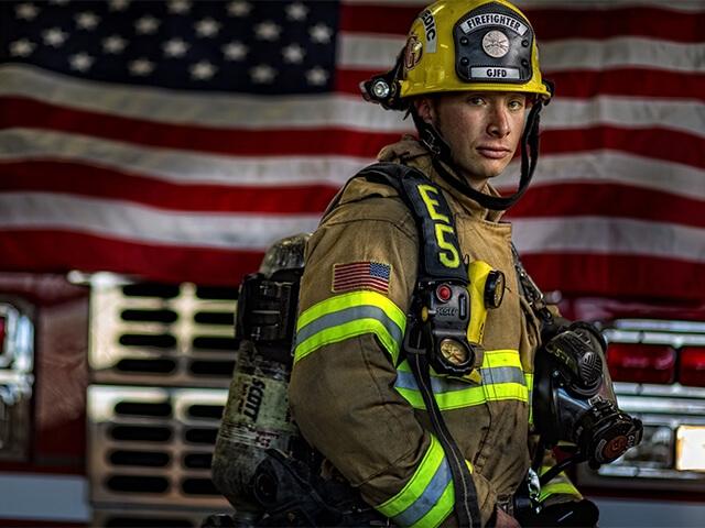 A firefighter stands in front of an American Flag. Personal Asset Retirement