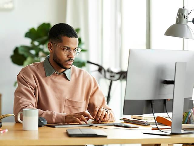 An African American man sits at computer, reviewing investments