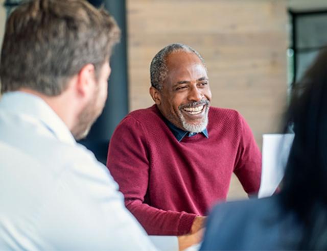 An employee sits with peers, talking and smiling