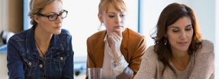 3 women sit at a table in conversation