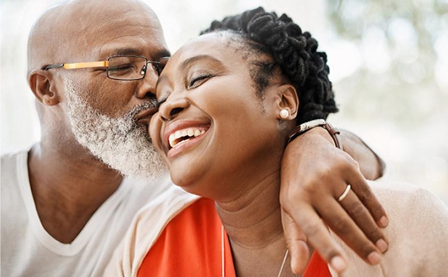 A man holds arm around wife and kisses her